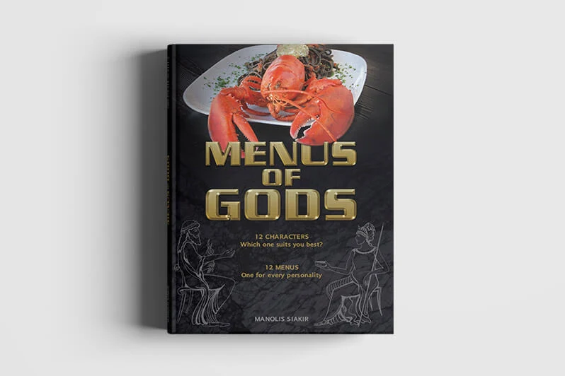 The cover of the cookbook “Menus of Gods” by Manolis Siakir, with a lobster on a plate on a black background