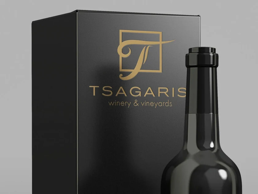 A black wine box with the gold Tsagaris winery & vineyards logo, next to a bottle